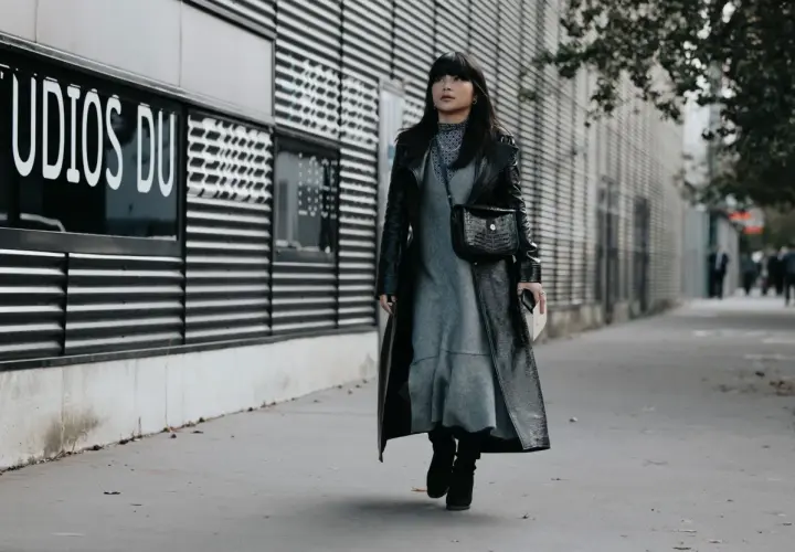 Une femme porte une robe grise et un long manteau noir verni, avec des bottines noires. Elle arbore un sac à main croco. Quelle chaussure mettre avec une robe noire et blanche ?