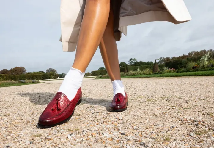 Une tenue avec chaussure rouge homme, des mocassins vernis à pampilles, portés avec des chaussettes blanches dans un jardin.