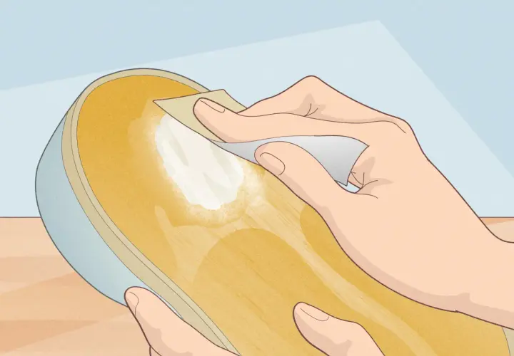 Main d'une personne appliquant une pâte blanche sur la semelle d'une chaussure, peut-être pour réparer une semelle qui se désagrège.