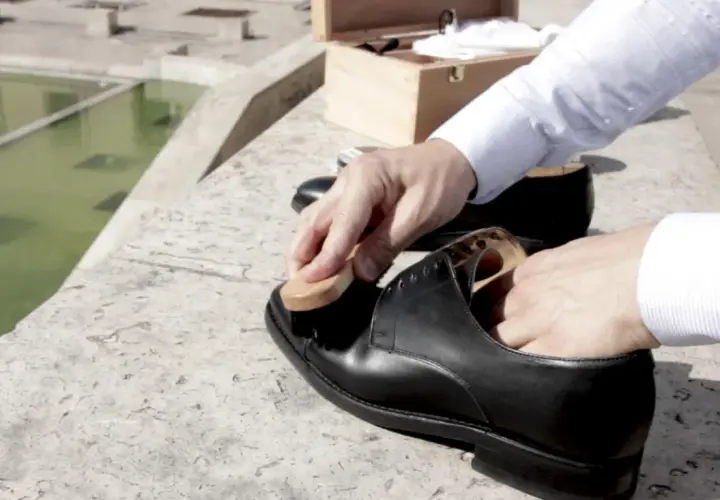 Un homme utilise une brosse pour faire briller ses chaussures en cuir noir, prêt pour une journée élégante.