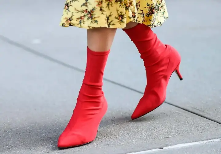 Pieds chaussés de bottines rouges audacieuses, assorties à une robe jaune à fleurs. Un look vibrant pour une journée en ville.
