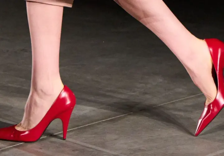 Pieds chaussés de talons aiguilles rouges brillants, symbolisant la confiance et le pouvoir.