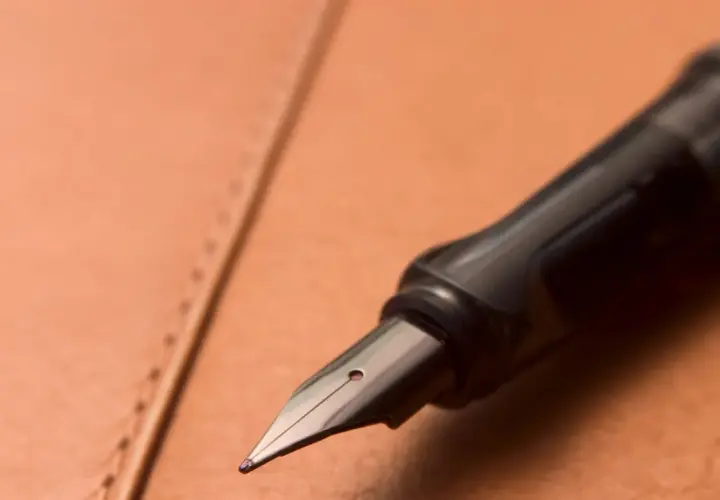 Plume d'un stylo plume noir sur un cuir brun. Une question se pose : comment enlever du stylo sur du cuir ?