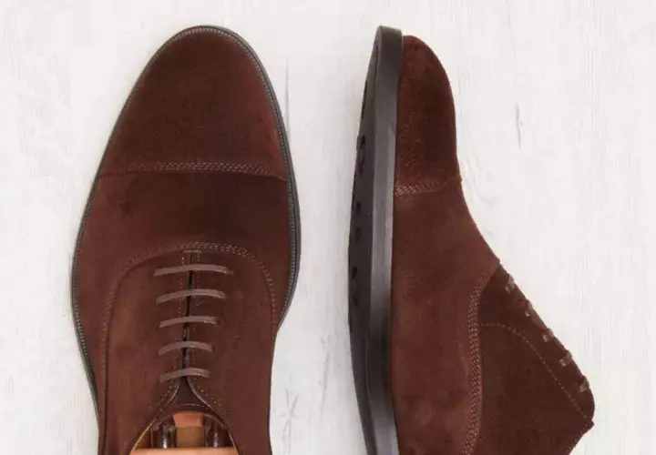 Deux chaussures richelieu en daim marron. La semelle est en cuir ou gomme, offrant confort et durabilité.