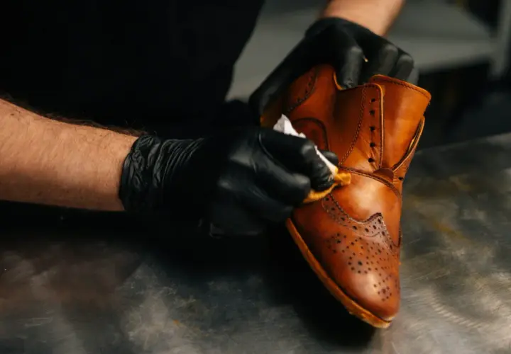 Gants noirs pour un entretien simili cuir. Un homme nettoie une chaussure marron avec un chiffon.