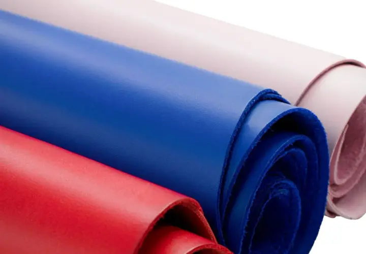 Rouleaux de cuir coloré, rouge, bleu et rose pâle, évoquant la douceur d'une vachette animal.
