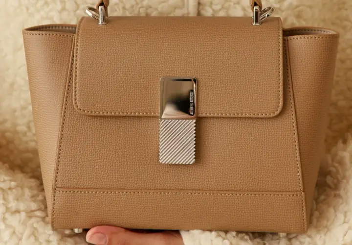 Sac à main élégant en cuir grainé camel, orné d'un fermoir métallique texturé.