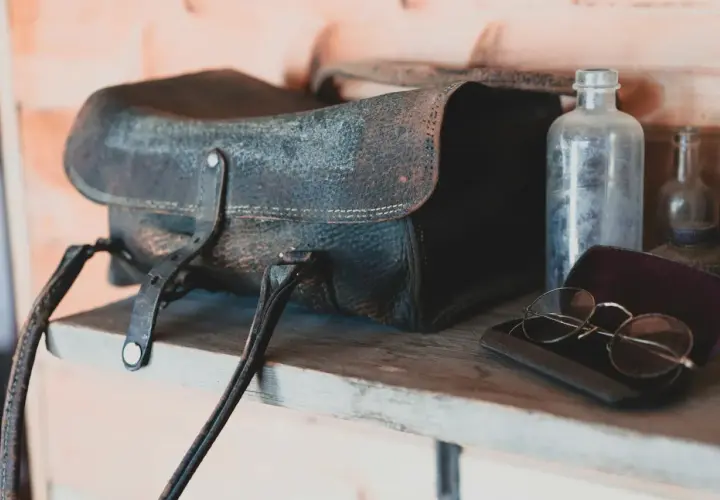 Sacoche en cuir moisi, lunettes anciennes et flacons poussiéreux sur une étagère. Le bicarbonate de soude pourrait aider à rafraîchir ce cuir.