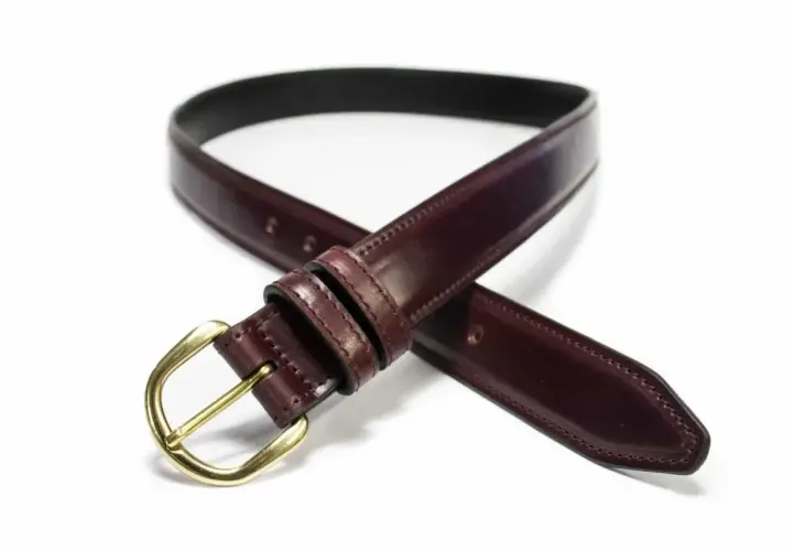Ceinture élégante en cuir cordovan bordeaux avec boucle dorée, un accessoire intemporel pour parfaire votre tenue.