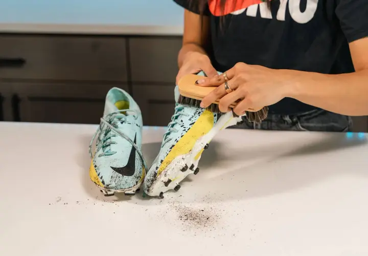 Nettoyage d'une chaussure de football sale, révélant une trace de frottement chaussure sur la semelle.