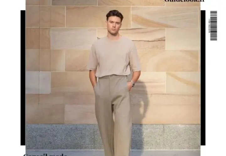 Un homme grand et mince porte un t-shirt beige et un pantalon ample. Un look parfait pour savoir comment s'habiller quand on est grande et mince.