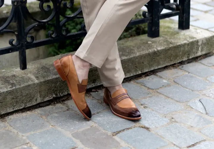 Un homme porte des mocassins bicolores en cuir, un style parfait pour une promenade en ville. Pas de marron dans la ville, juste du style !