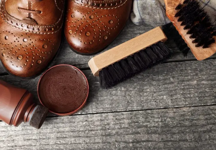 Paire de chaussures en cuir marron, cirage, applicateur et brosses pour vernir chaussures.