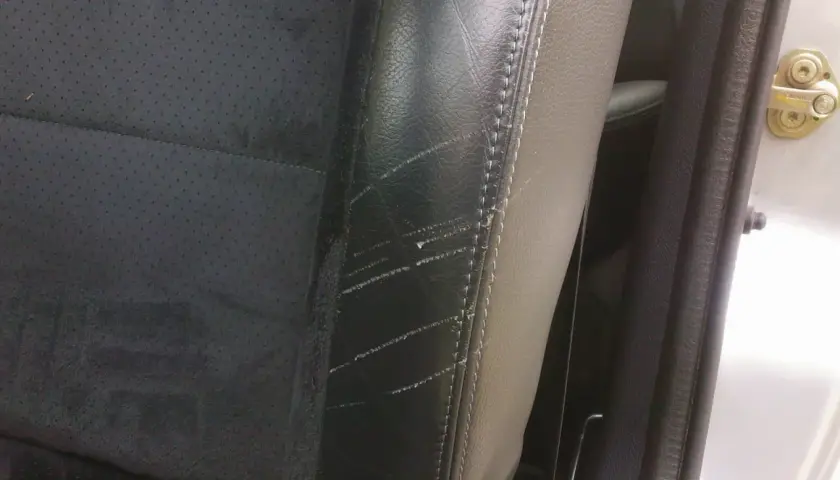 Siège de voiture en cuir noir avec des rayures visibles sur le côté, un problème courant pour ceux qui cherchent comment enlever les rayures sur chaussures vernis.