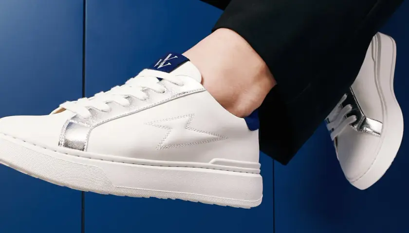 Baskets blanches homme avec détails argentés et logo bleu. Parfaites avec un pantalon noir, elles répondent à la question : quelles chaussettes avec baskets blanches homme ?