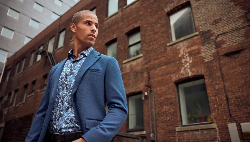 Un homme porte un costume bleu avec une chemise à motifs floraux, prêt à porter des bas au bureau.