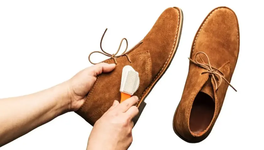 Nettoyage d'une chaussure en cuir retourné avec une brosse.