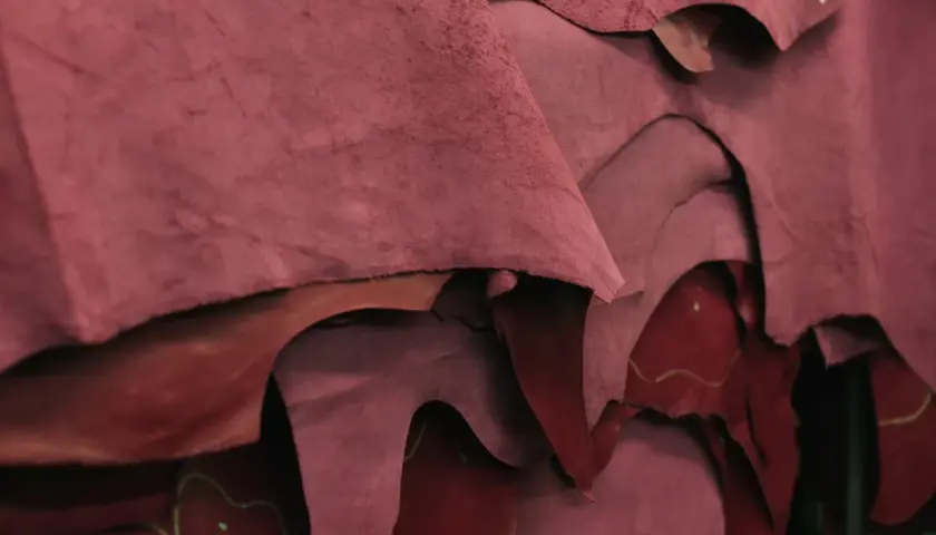 Superposition de pièces de croute de cuir bordeaux, matière brute prête à être transformée.