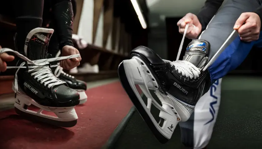 Des patineurs se préparent à entrer sur la glace, ils commencent à **poser soi même patin chaussure** pour le match.