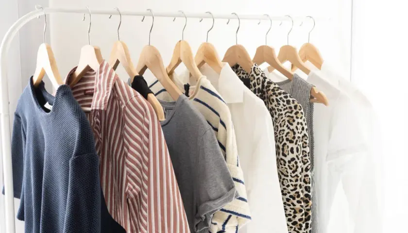 Vêtements sur un portant : une garde-robe minimaliste pour comment éviter la surconsommation. Bleu, rayé, léopard, blanc... des pièces intemporelles.