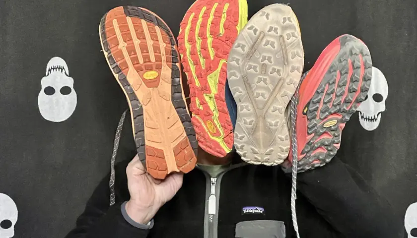 Qu'est-ce qu'une semelle Vibram ? Quatre semelles de chaussures de trail, dont une Vibram orange, montrent leur adhérence.