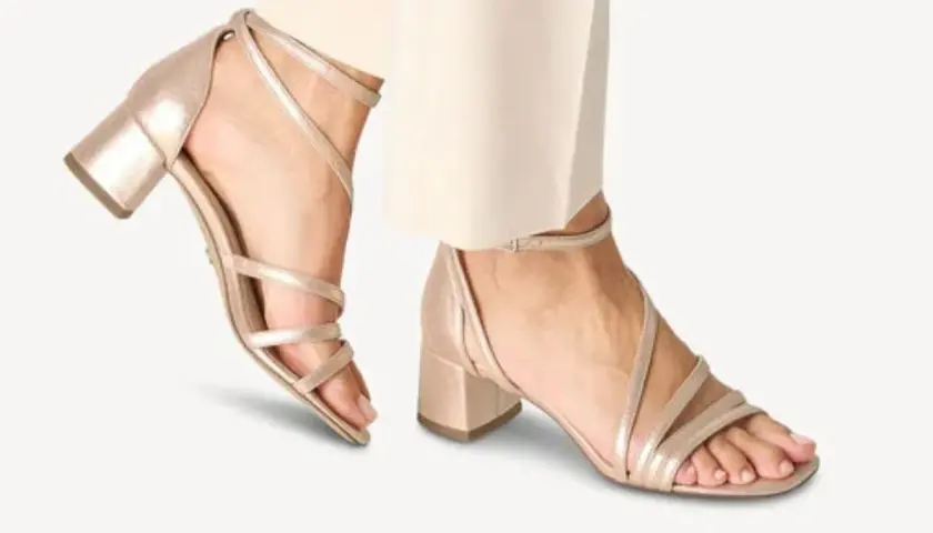 Sandales à talons carrés dorées, avec brides fines croisées sur le pied. Quel vernis avec chaussures dorées ? Un nude ou un rose pâle serait parfait.