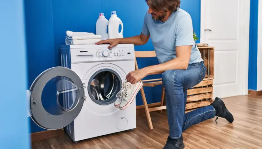 Un homme prépare ses baskets pour le lavage. Il se demande à combien laver des chaussures pour qu'elles ressortent comme neuves.