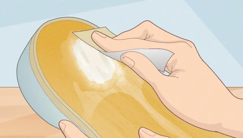 Main d'une personne appliquant une pâte blanche sur la semelle d'une chaussure, peut-être pour réparer une semelle qui se désagrège.