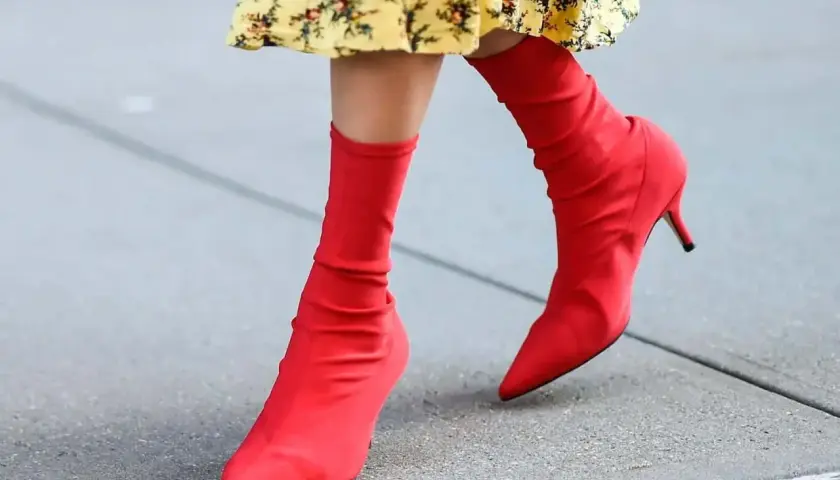 Pieds chaussés de bottines rouges audacieuses, assorties à une robe jaune à fleurs. Un look vibrant pour une journée en ville.