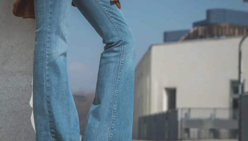 Un jean bootcut bleu clair, un pull marron et des baskets. Style décontracté pour une journée ensoleillée.