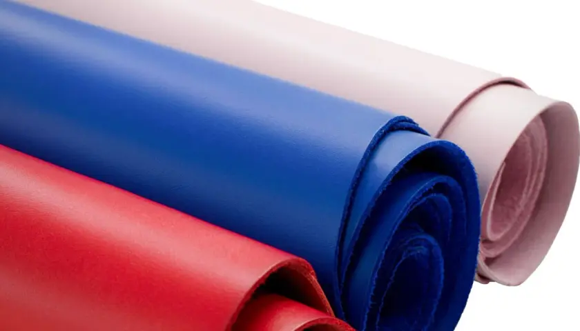 Rouleaux de cuir coloré, rouge, bleu et rose pâle, évoquant la douceur d'une vachette animal.