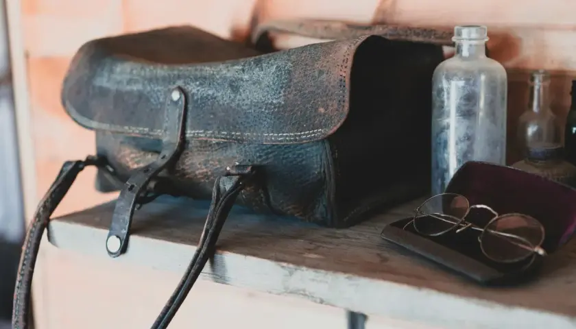 Sacoche en cuir moisi, lunettes anciennes et flacons poussiéreux sur une étagère. Le bicarbonate de soude pourrait aider à rafraîchir ce cuir.