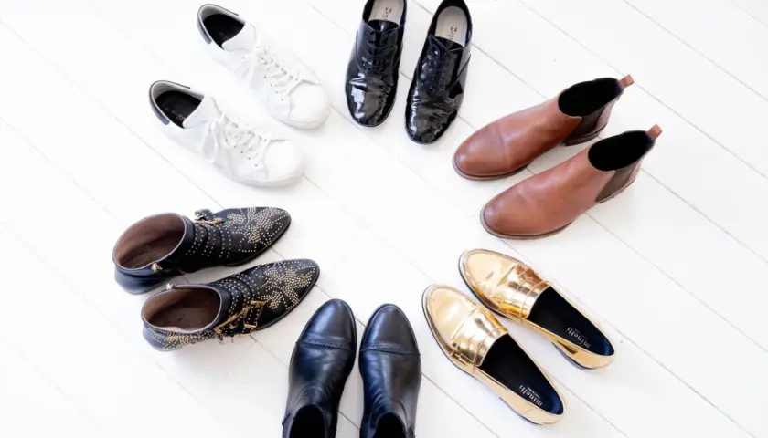 Collection de chaussures variées : baskets blanches, bottines cloutées, mocassins dorés, bottines noires, derbies vernies et bottines marron. Une vraie panoplie de chaussure qui va avec tout !