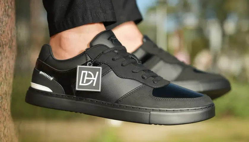 Baskets noires stylées, avec un jean qui détient sur la chaussure. Logo DH sur une étiquette.