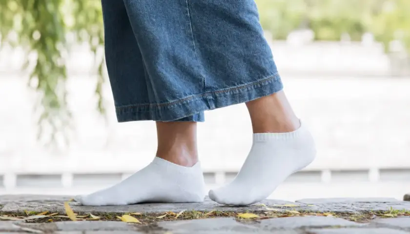 Pieds féminins en chaussettes blanches discrètes, idéales avec des baskets blanches pour un look casual.