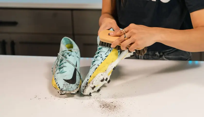 Nettoyage d'une chaussure de football sale, révélant une trace de frottement chaussure sur la semelle.