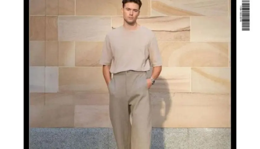 Un homme grand et mince porte un t-shirt beige et un pantalon ample. Un look parfait pour savoir comment s'habiller quand on est grande et mince.