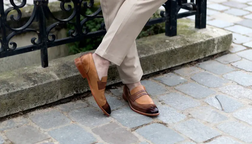 Un homme porte des mocassins bicolores en cuir, un style parfait pour une promenade en ville. Pas de marron dans la ville, juste du style !