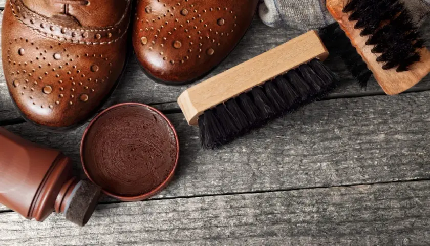 Paire de chaussures en cuir marron, cirage, applicateur et brosses pour vernir chaussures.
