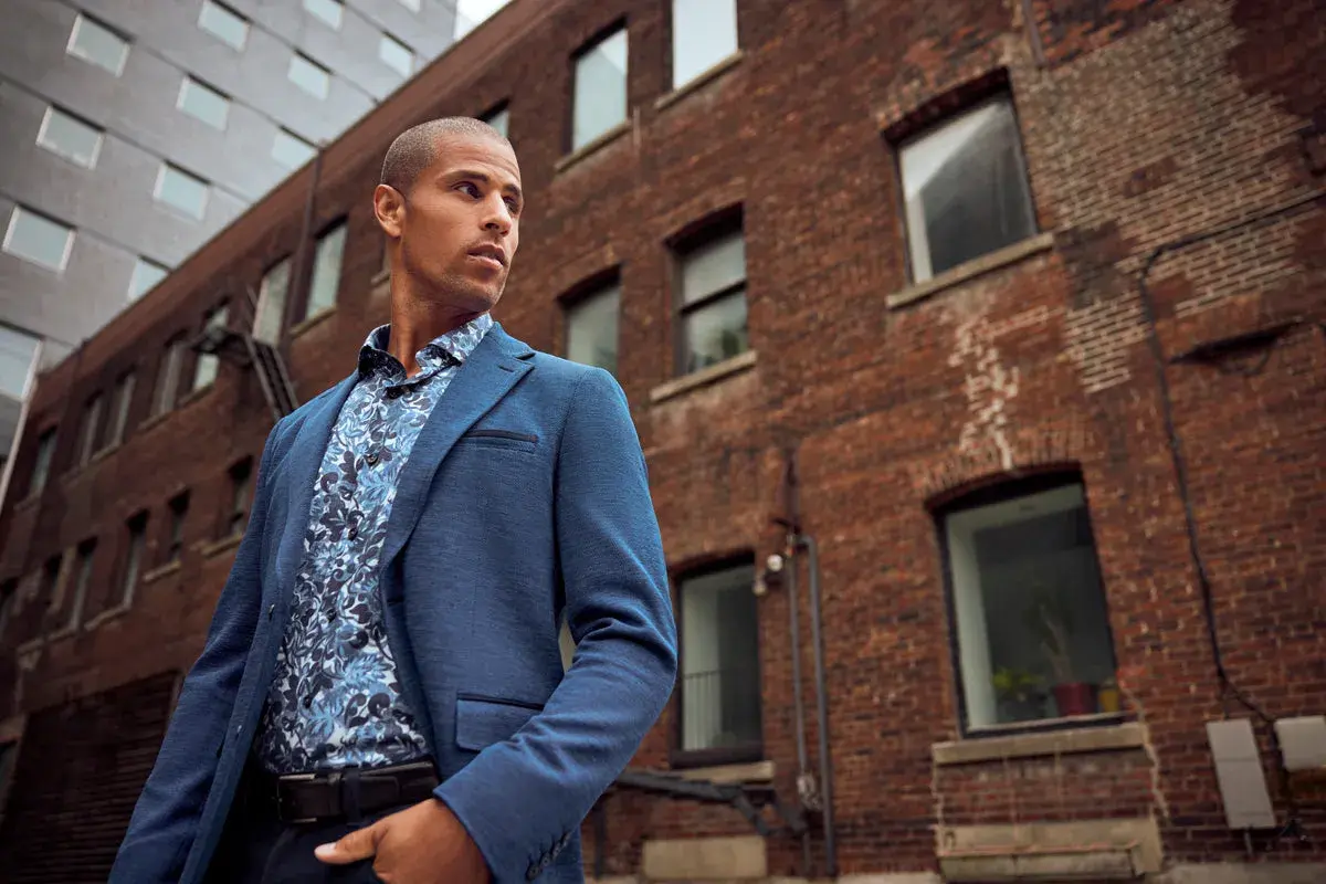 Un homme porte un costume bleu avec une chemise à motifs floraux, prêt à porter des bas au bureau.