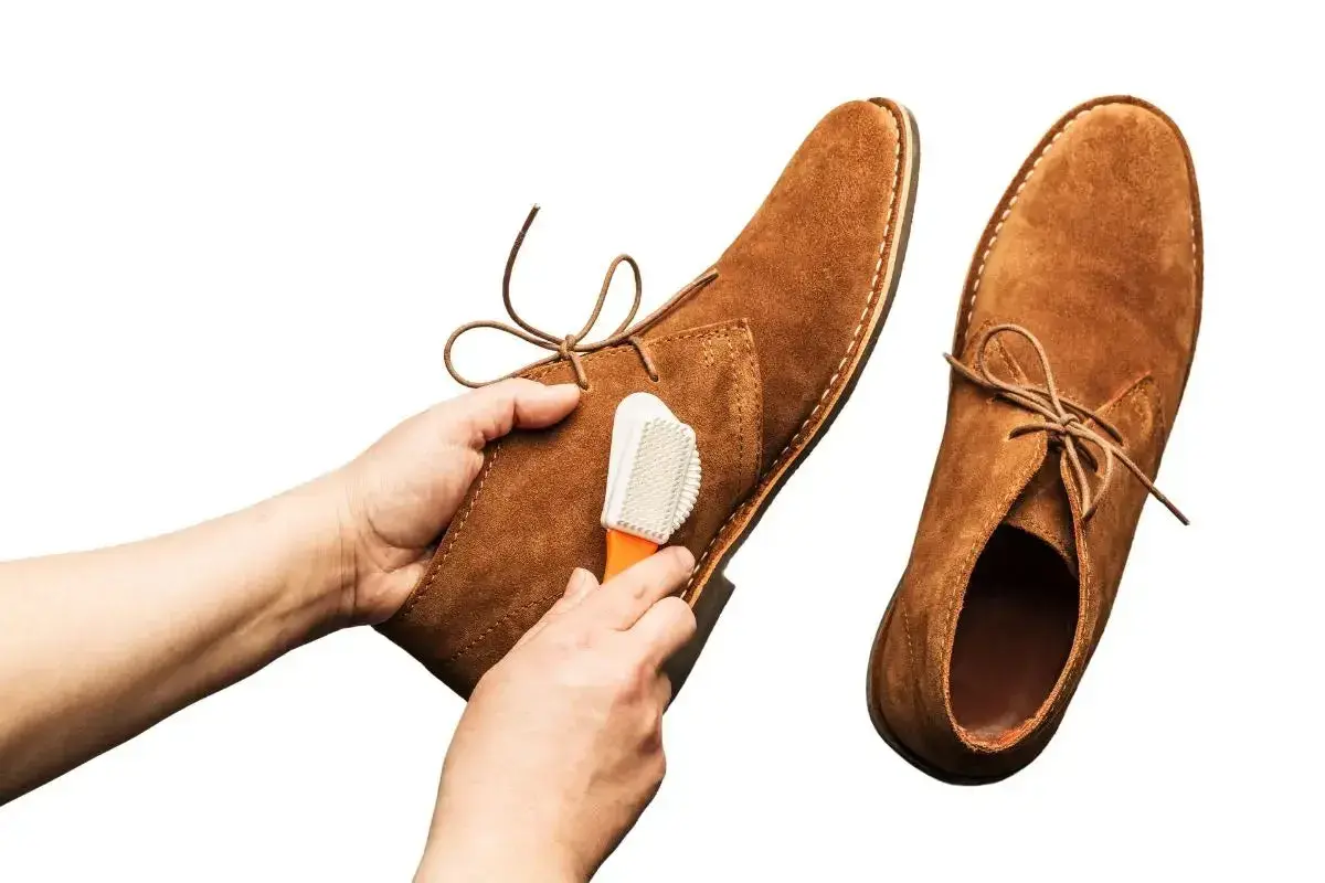 Nettoyage d'une chaussure en cuir retourné avec une brosse.