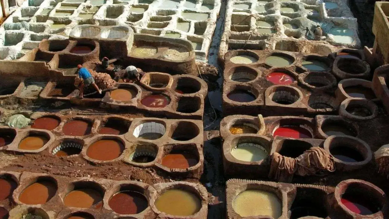 Des cuves remplies de pigments naturels montrent comment est fait le cuir. Des artisans travaillent dans ces bassins de teinture traditionnels.