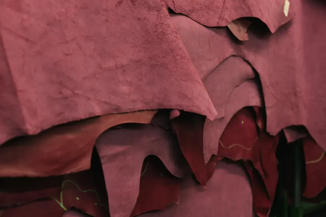 Superposition de pièces de croute de cuir bordeaux, matière brute prête à être transformée.