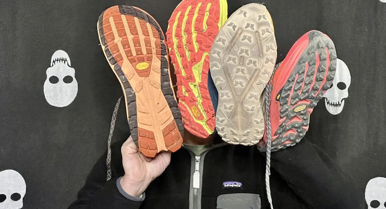 Qu'est-ce qu'une semelle Vibram ? Quatre semelles de chaussures de trail, dont une Vibram orange, montrent leur adhérence.
