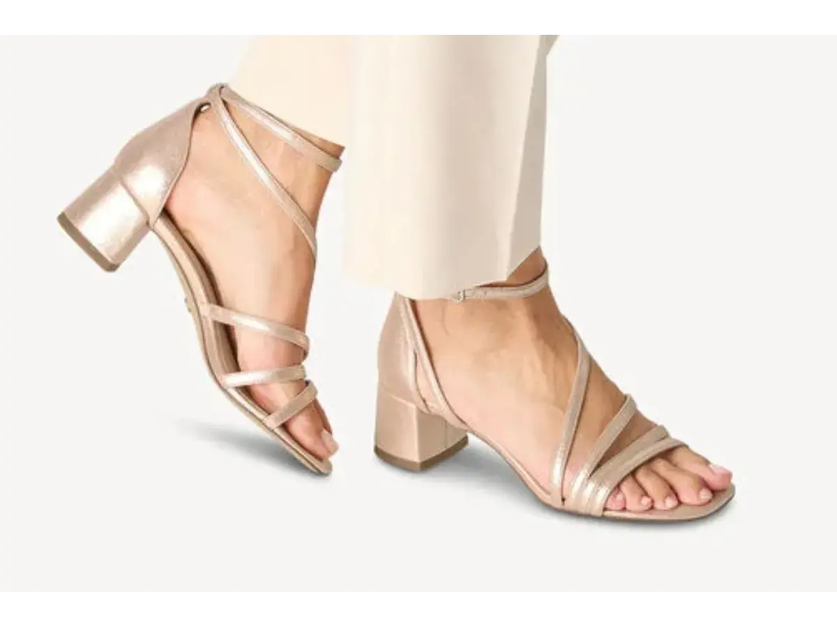 Sandales à talons carrés dorées, avec brides fines croisées sur le pied. Quel vernis avec chaussures dorées ? Un nude ou un rose pâle serait parfait.