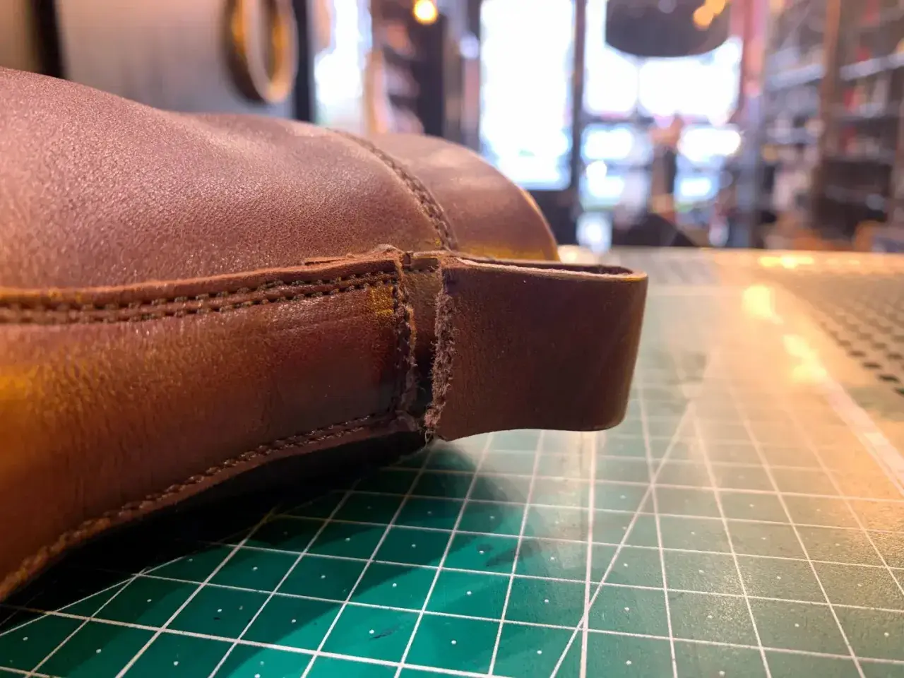 Gros plan sur une chaussure en cuir marron, montrant une déchirure à réparer. Le travail de réparation du cuir déchiré d'une chaussure est en cours.