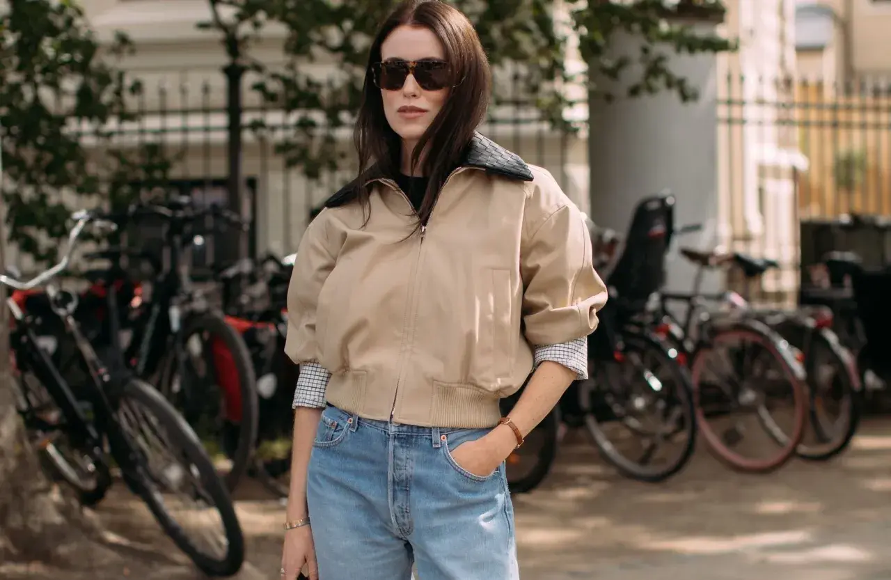 Une femme avec une morphologie H porte un jean bleu délavé et une veste beige.