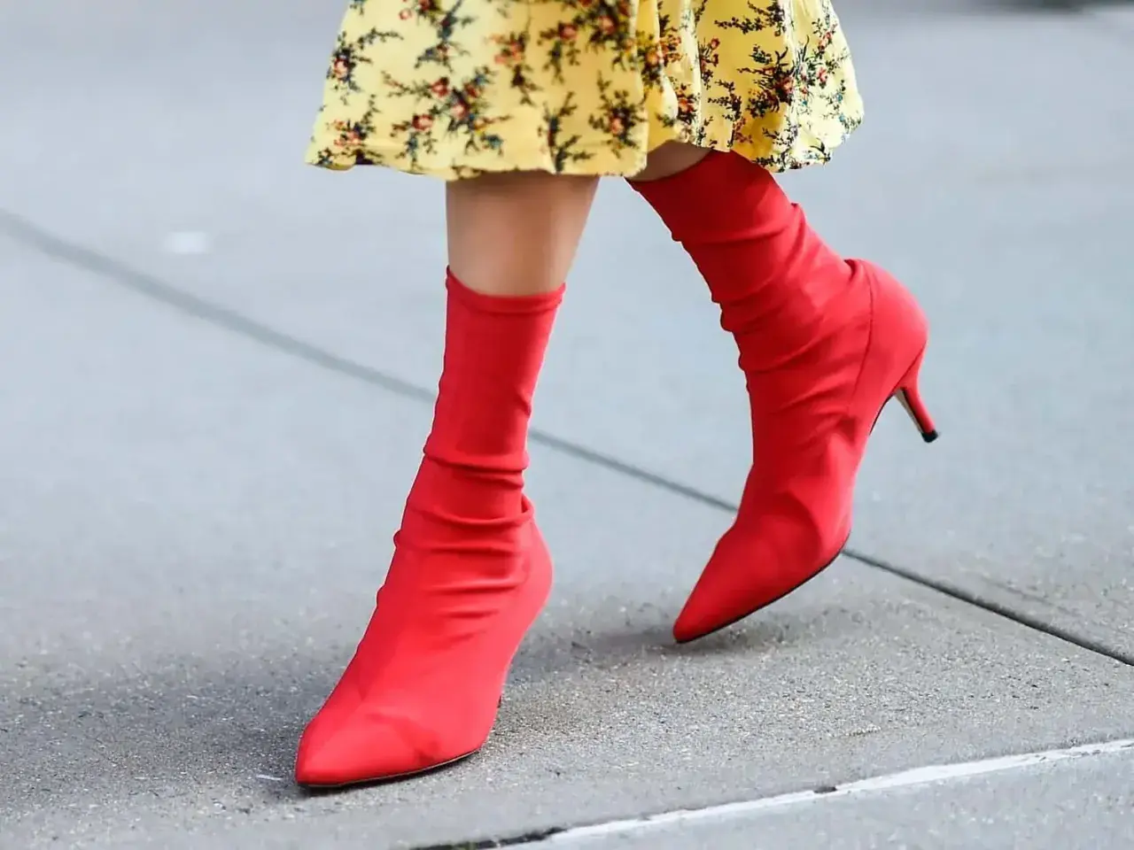 Pieds chaussés de bottines rouges audacieuses, assorties à une robe jaune à fleurs. Un look vibrant pour une journée en ville.
