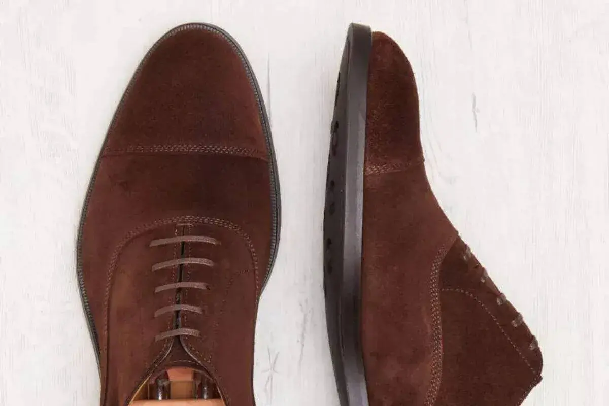 Deux chaussures richelieu en daim marron. La semelle est en cuir ou gomme, offrant confort et durabilité.