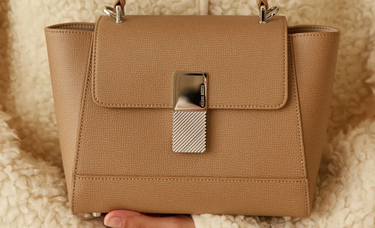 Sac à main élégant en cuir grainé camel, orné d'un fermoir métallique texturé.
